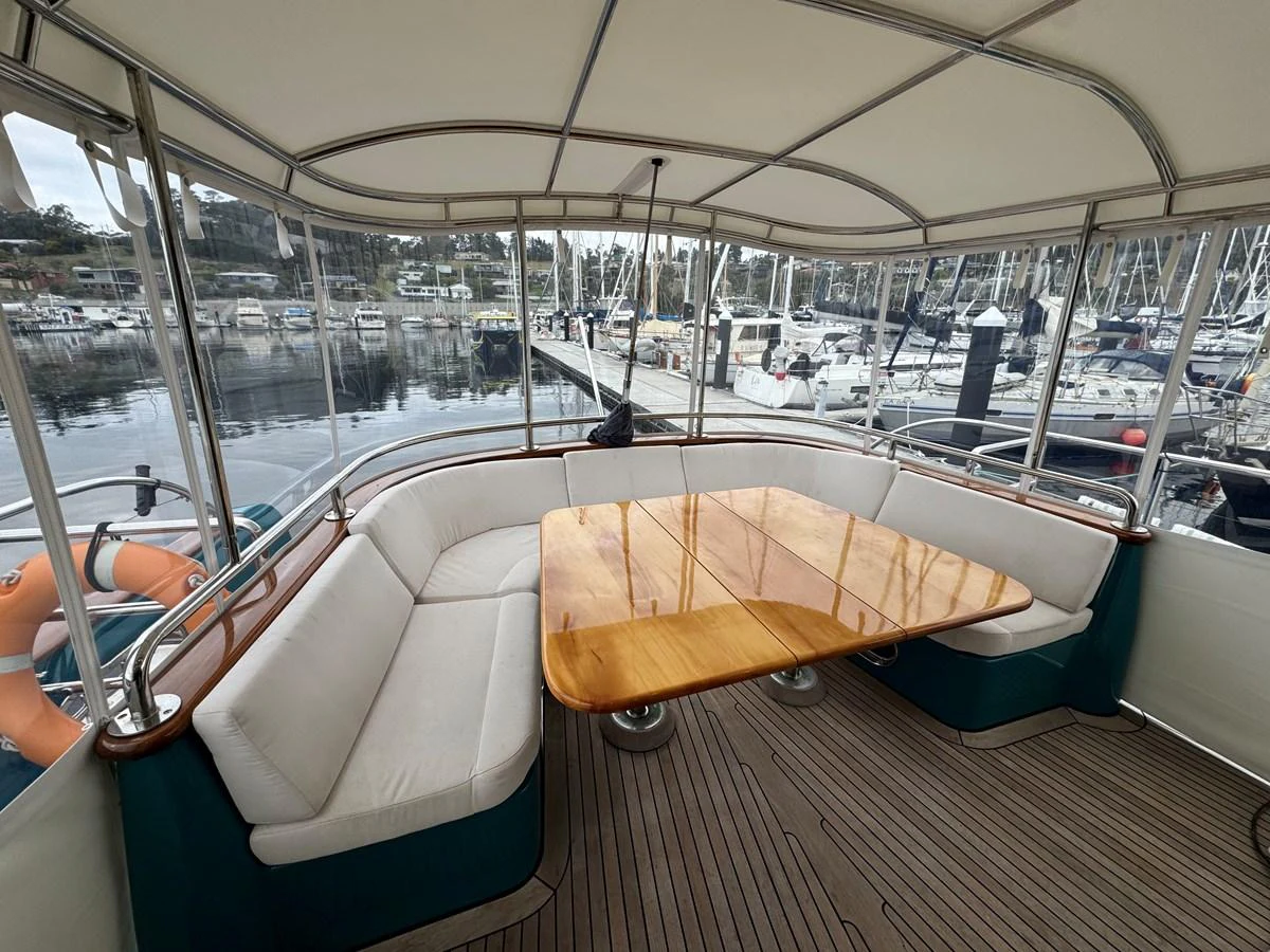 The aft deck features a cozy seating area with a wooden table, perfect for enjoying meals with a view of the marina. aboard SV TEAL Yacht for Sale