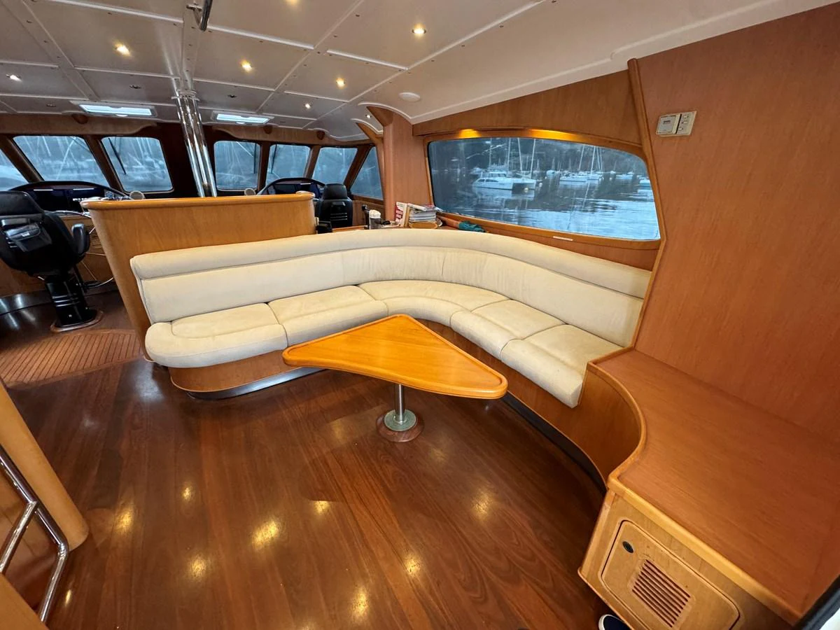 The yacht's salon features a curved beige sofa and a wooden coffee table, creating a cozy and inviting atmosphere. aboard SV TEAL Yacht for Sale