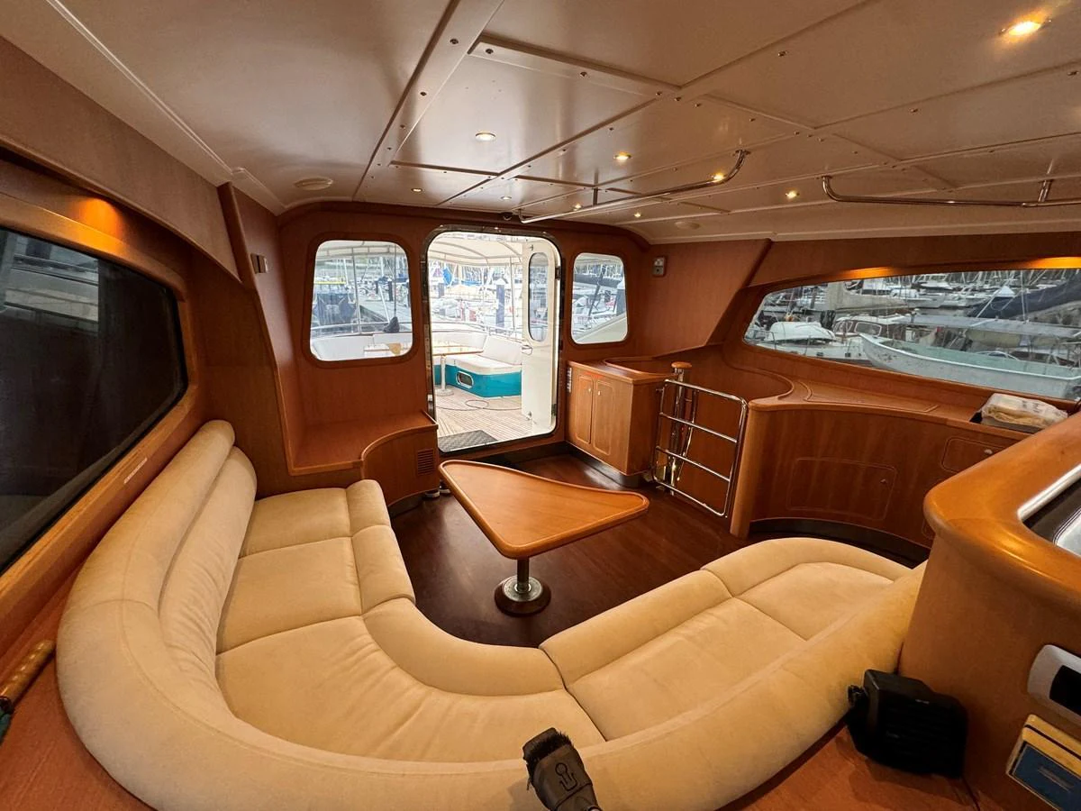 The yacht's salon features a cozy, curved seating area with large windows offering a view of the marina. aboard SV TEAL Yacht for Sale