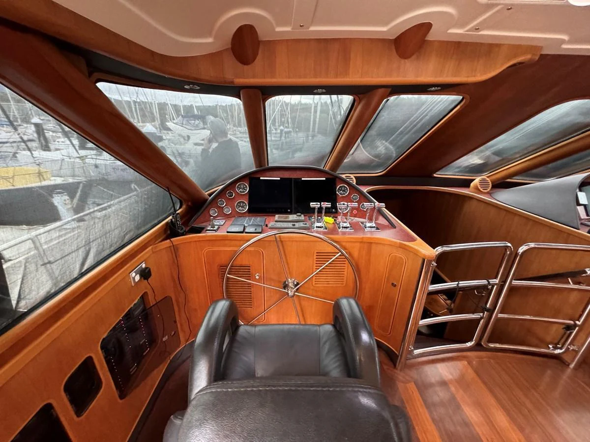 The helm station features a classic wooden dashboard with modern navigation instruments and a comfortable captain's chair. aboard SV TEAL Yacht for Sale