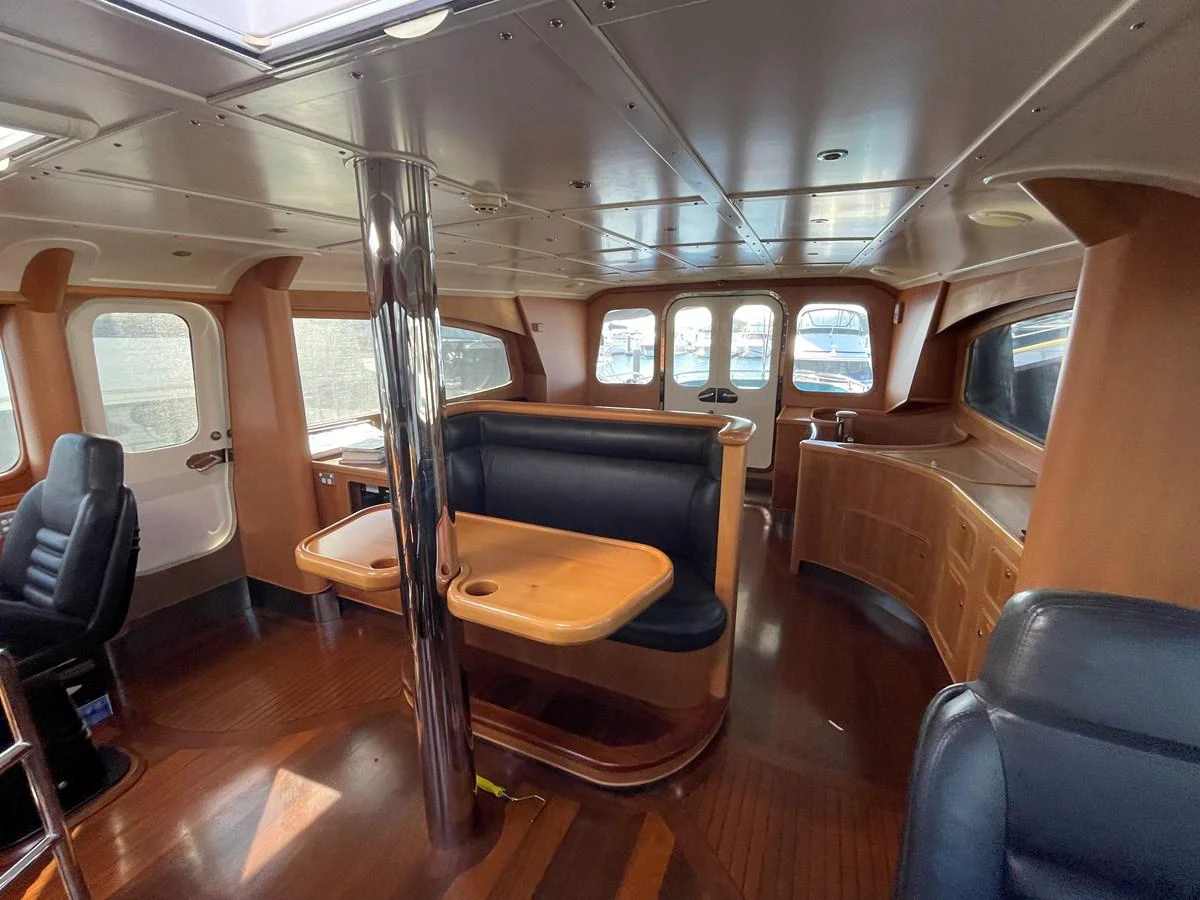The yacht's interior features a spacious seating area with wooden accents and large windows for natural light. aboard SV TEAL Yacht for Sale