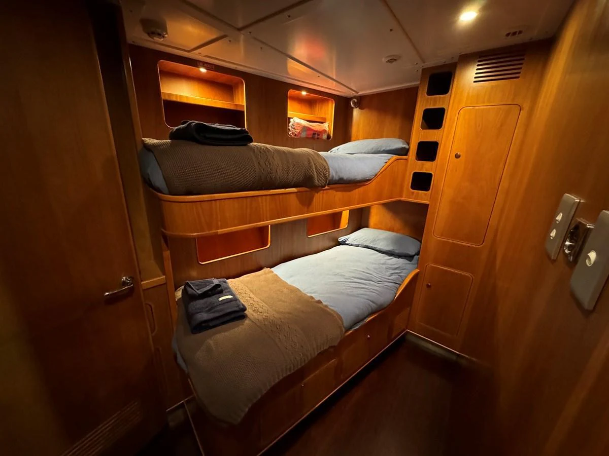 The cozy bunk room features warm wood paneling and comfortable bedding. aboard SV TEAL Yacht for Sale