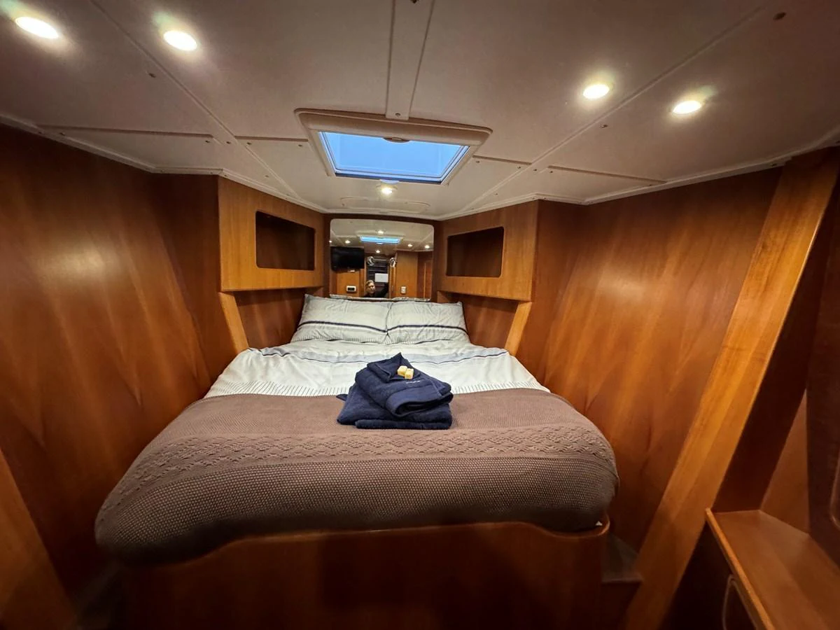 A cozy stateroom with a comfortable bed and warm wooden paneling. aboard SV TEAL Yacht for Sale