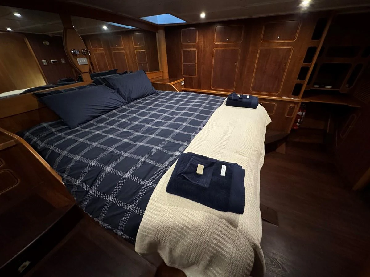 The master stateroom features a spacious bed with luxurious linens and warm wood finishes. aboard SV TEAL Yacht for Sale