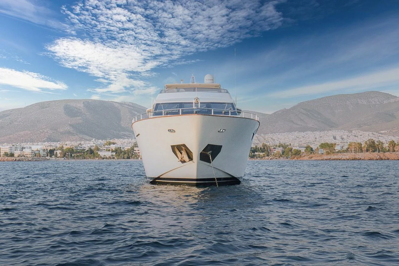 A luxurious yacht is anchored on calm waters with a scenic mountainous backdrop. aboard D-FORCE Yacht for Sale
