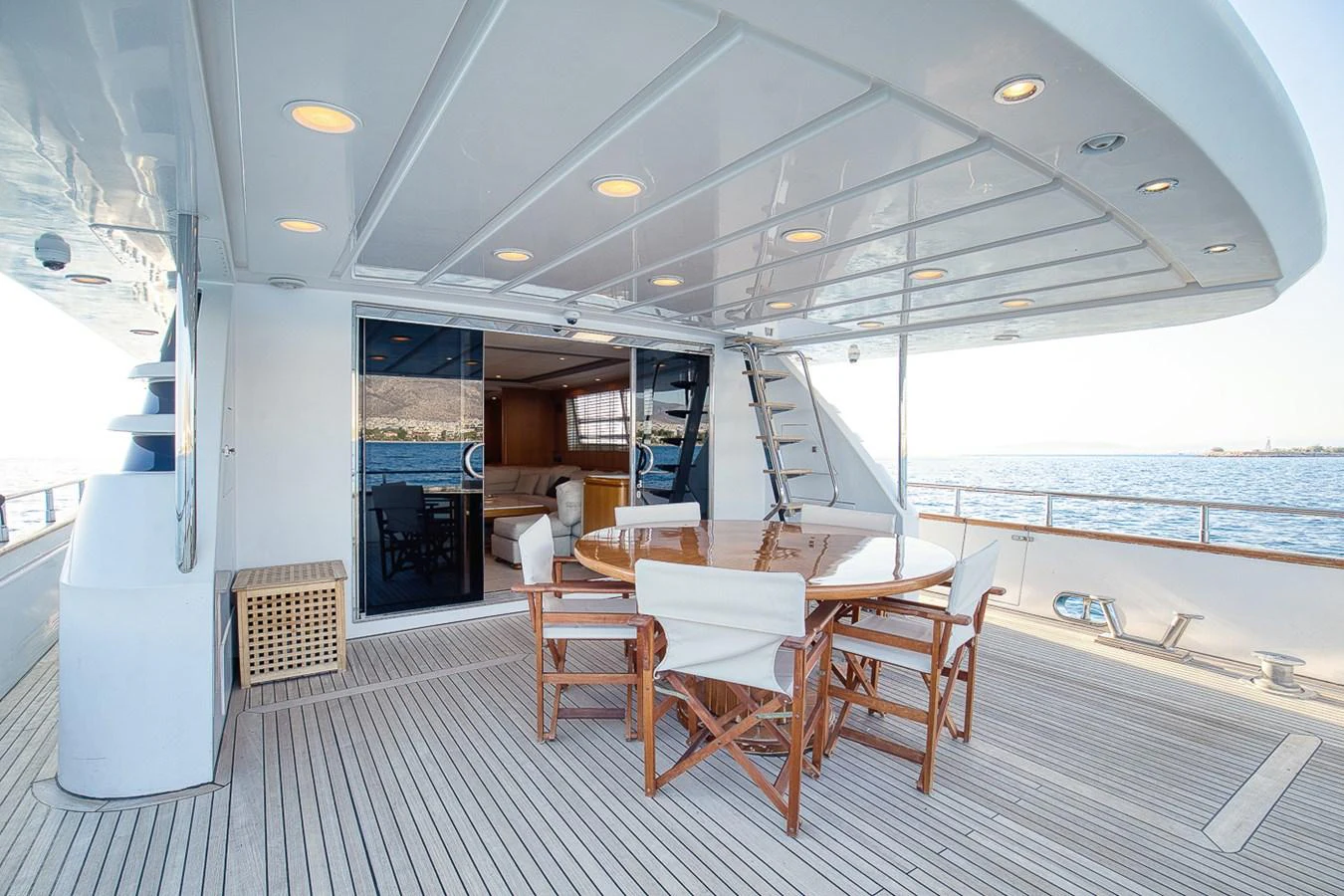 The aft deck features a stylish dining area with a wooden table and comfortable chairs, perfect for alfresco dining with a view of the sea. aboard D-FORCE Yacht for Sale