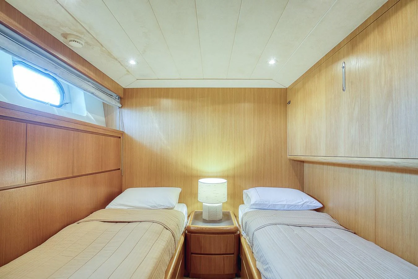 The twin stateroom offers a cozy and inviting space with two single beds and warm wooden finishes. aboard D-FORCE Yacht for Sale
