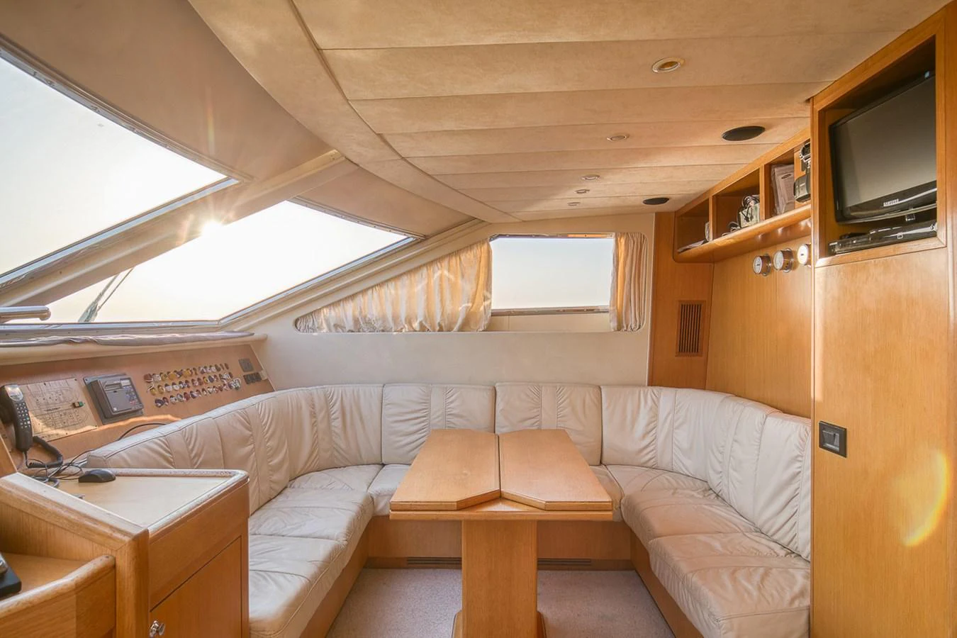 The saloon features a cozy seating area with a wooden table and ample natural light. aboard D-FORCE Yacht for Sale