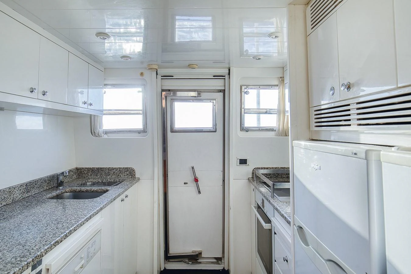 The yacht's galley features sleek white cabinetry and modern appliances, creating a bright and functional space. aboard D-FORCE Yacht for Sale