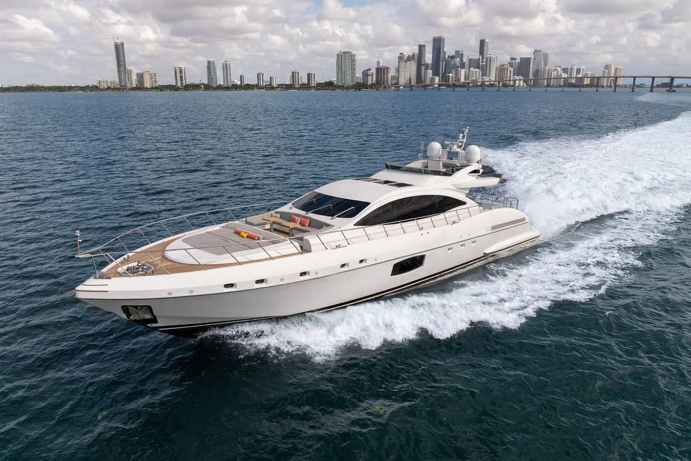 A sleek yacht cruises through the water with a city skyline in the background. aboard SAYONARA Yacht for Sale
