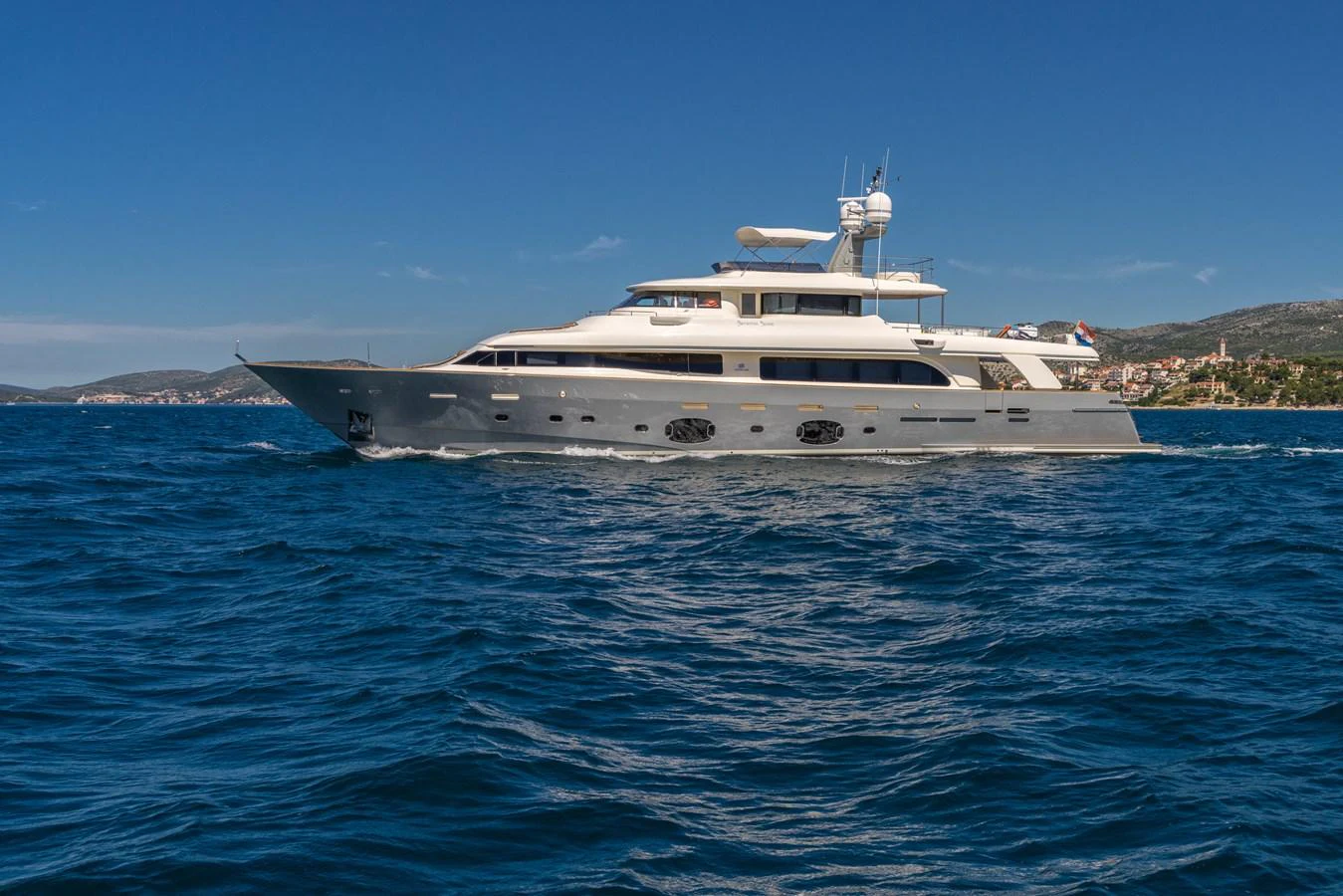 A sleek and elegant yacht cruises through the open water under a clear blue sky. aboard SEVENTH SENSE Yacht for Sale