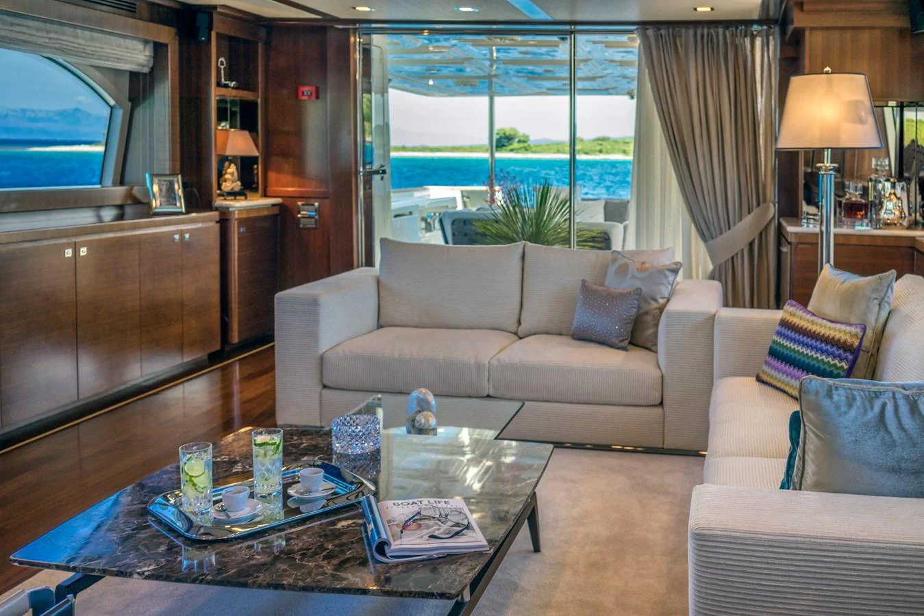 The yacht's salon features elegant seating with a view of the ocean through large windows. aboard SEVENTH SENSE Yacht for Sale