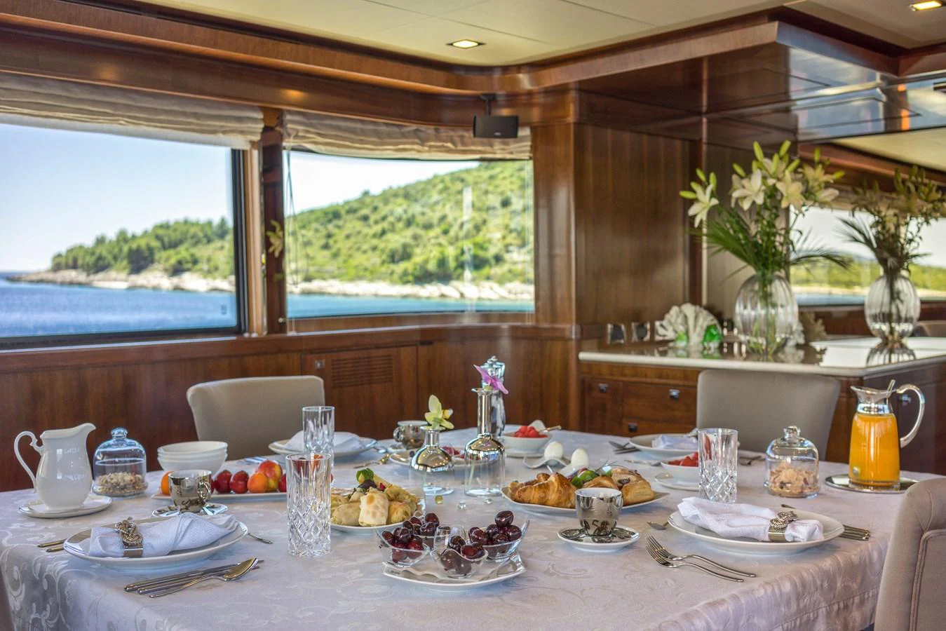The yacht's dining area features an elegantly set table with a scenic view through large windows. aboard SEVENTH SENSE Yacht for Sale