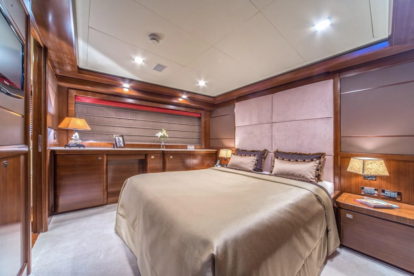 The master stateroom features a luxurious bed with elegant lighting and wood finishes. aboard SEVENTH SENSE Yacht for Sale
