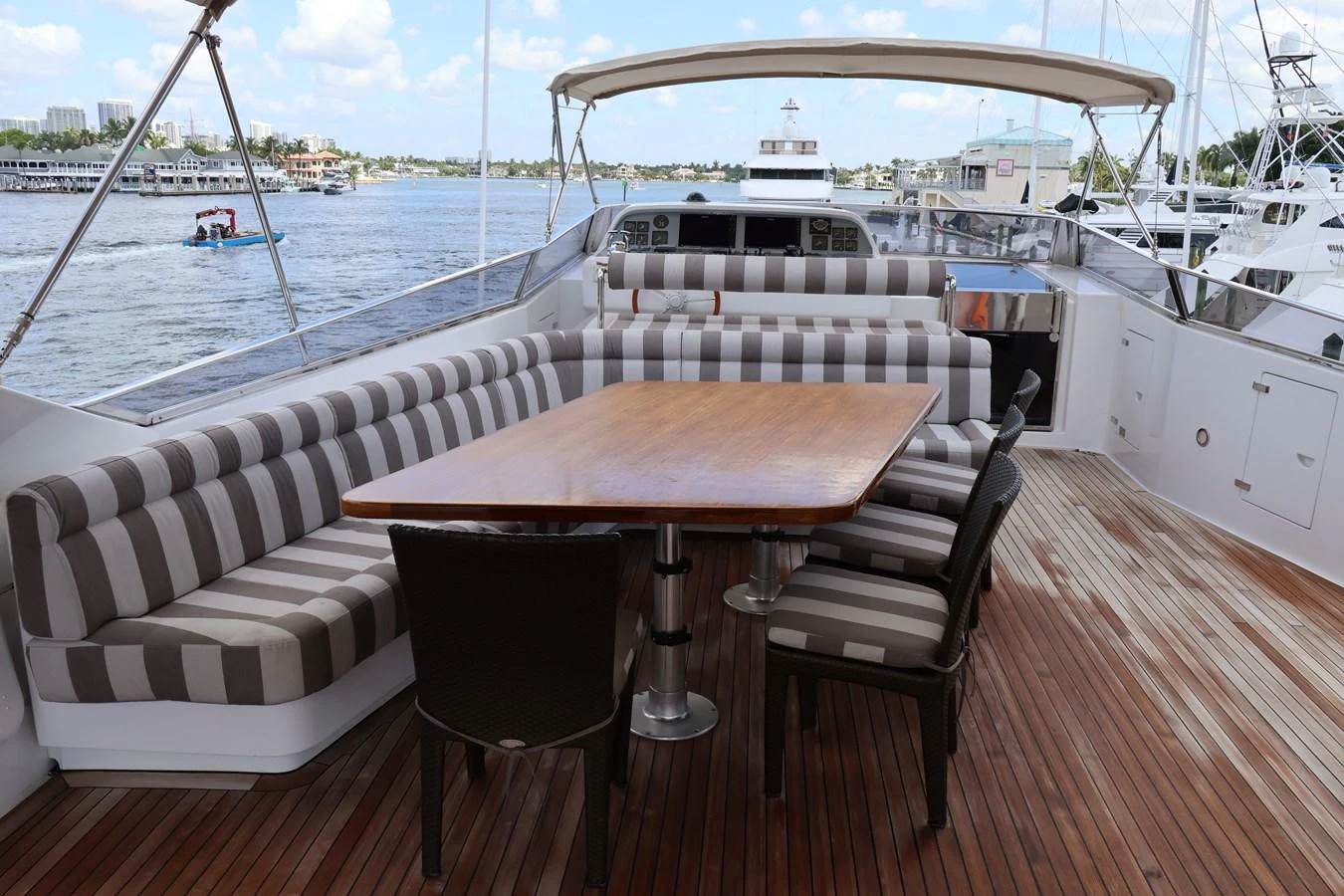 The aft deck features a spacious seating area with a large wooden table, perfect for outdoor dining and relaxation. aboard Q Yacht for Sale