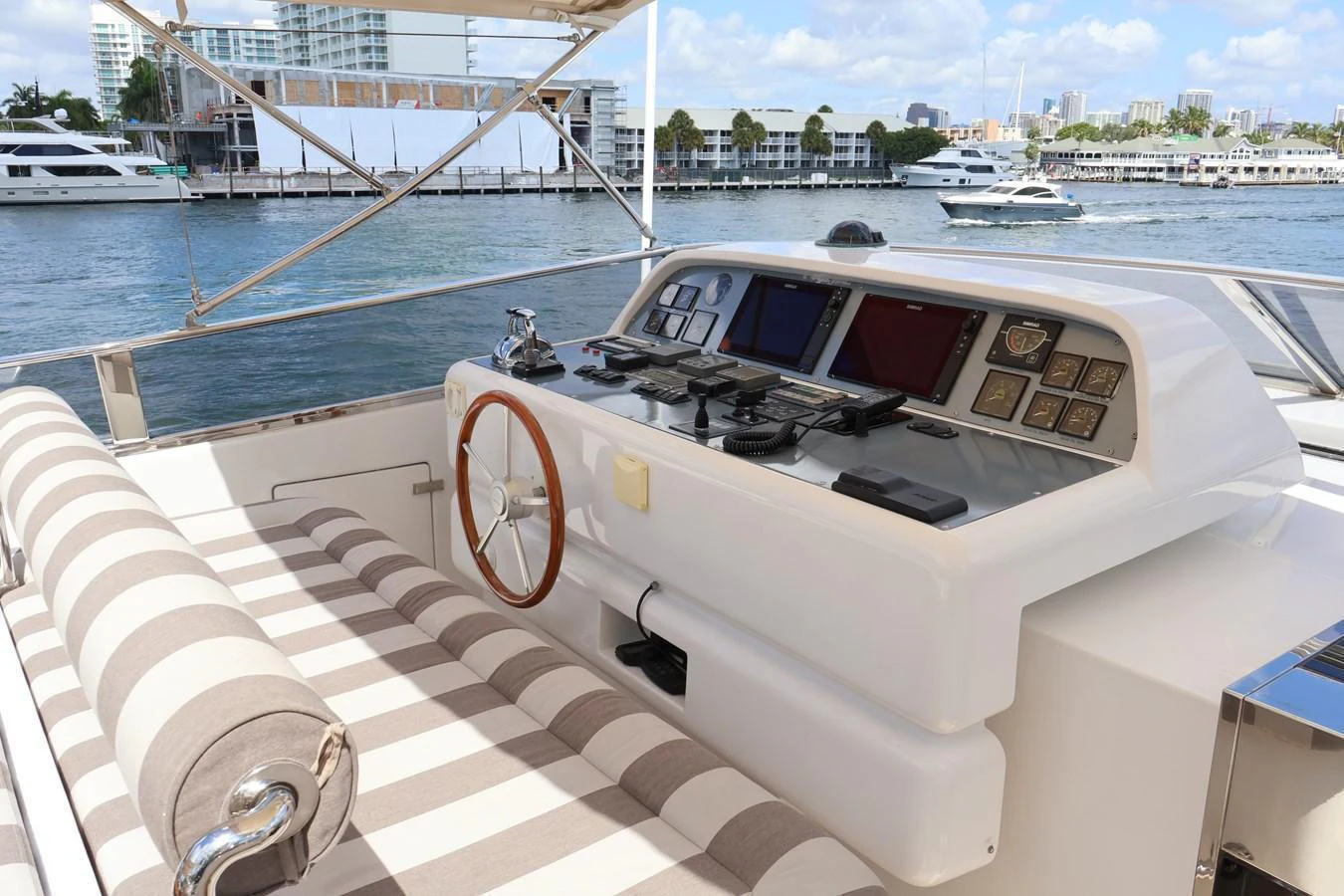The helm station features a sleek control panel and comfortable striped seating, offering a commanding view of the water. aboard Q Yacht for Sale
