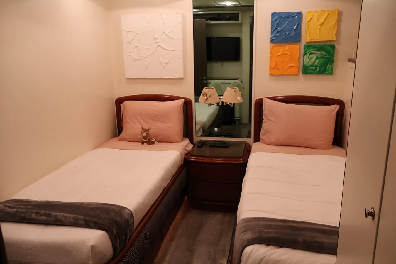 A cozy twin stateroom with modern art and soft lighting. aboard Q Yacht for Sale
