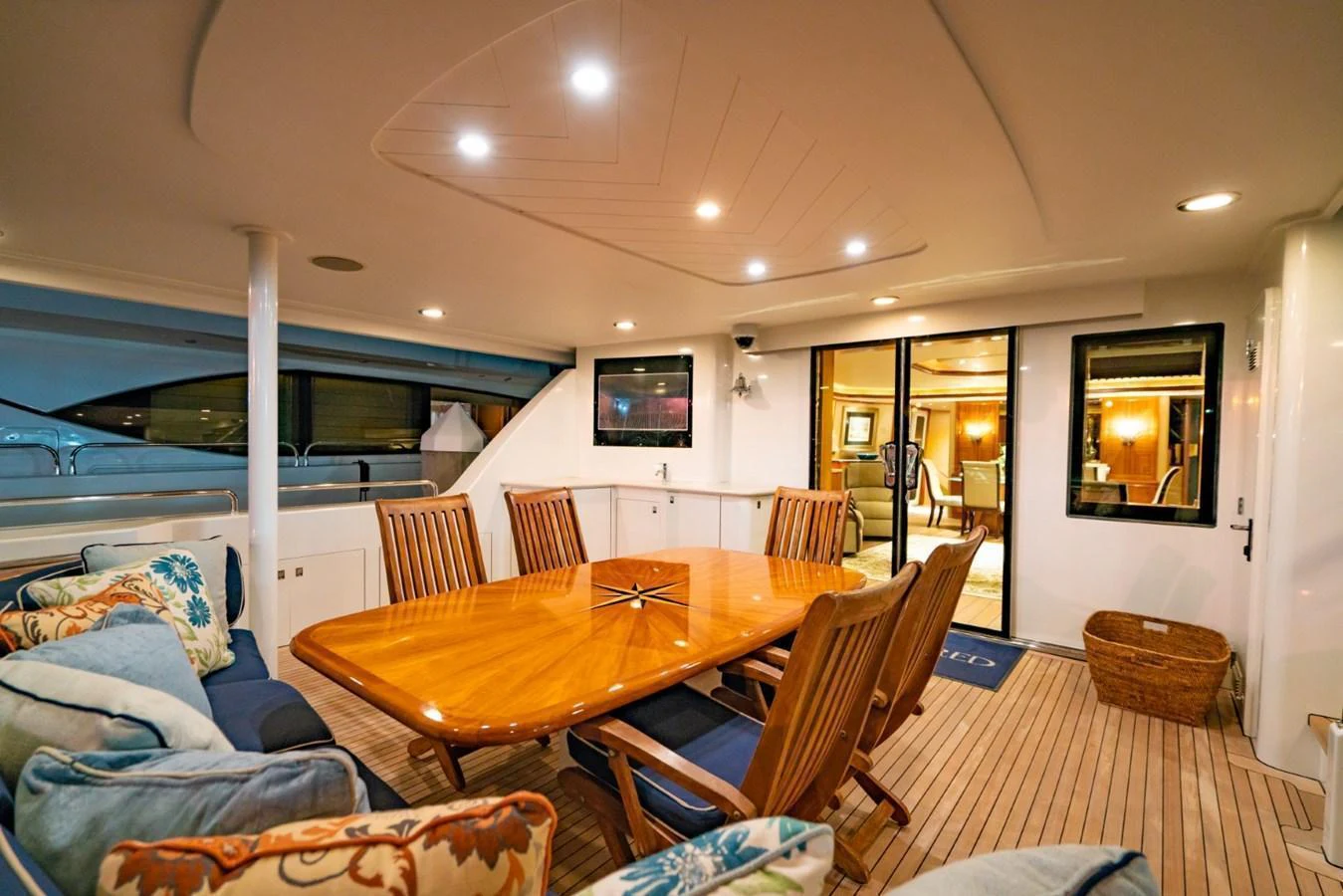 The aft deck features a spacious dining area with a polished wooden table and comfortable seating, perfect for alfresco dining. aboard SNOWBORED Yacht for Sale