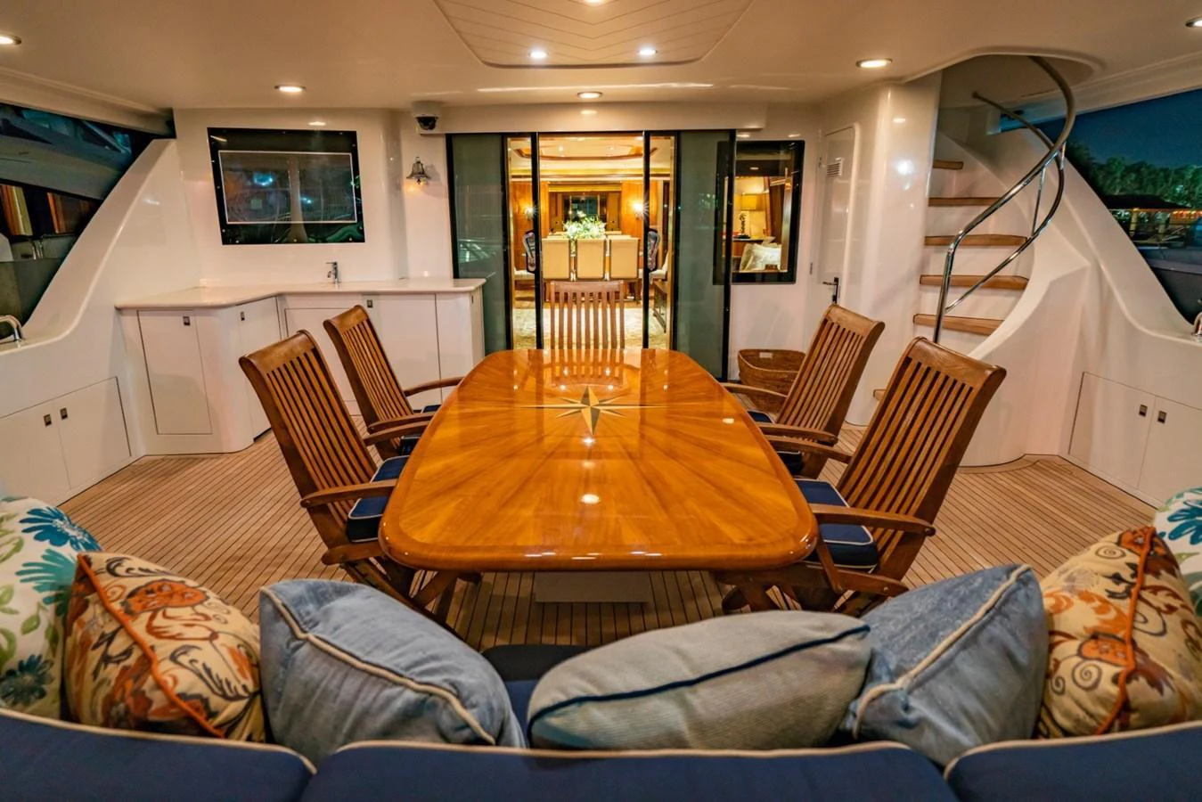 The aft deck features a spacious dining area with a polished wooden table and comfortable seating, perfect for alfresco dining. aboard SNOWBORED Yacht for Sale