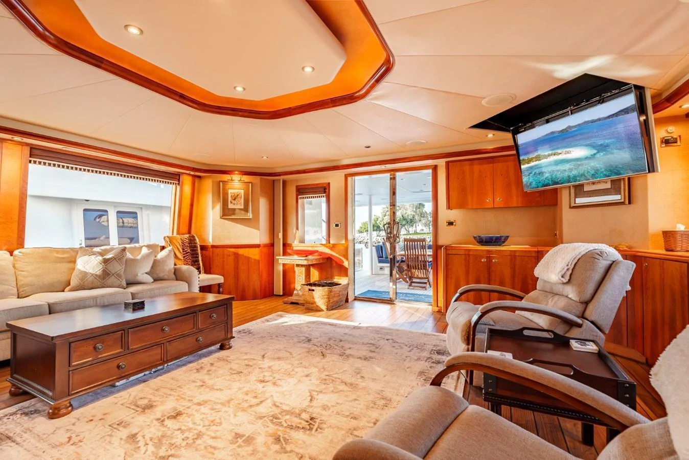The salon features plush seating, a large flat-screen TV, and ample natural light from large windows and a sliding door. aboard SNOWBORED Yacht for Sale