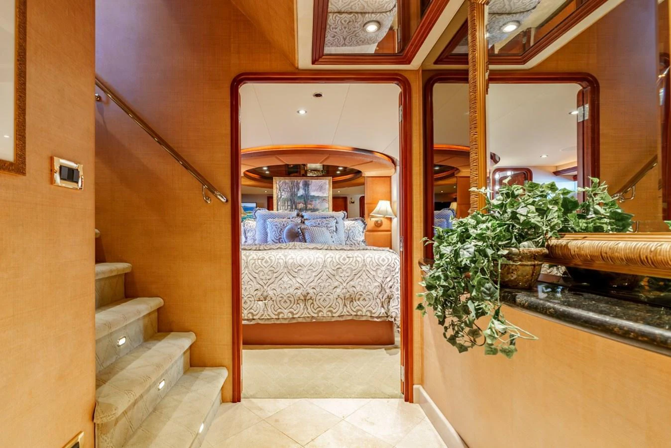 A luxurious stateroom with elegant bedding and warm lighting, accessed by a small staircase. aboard SNOWBORED Yacht for Sale