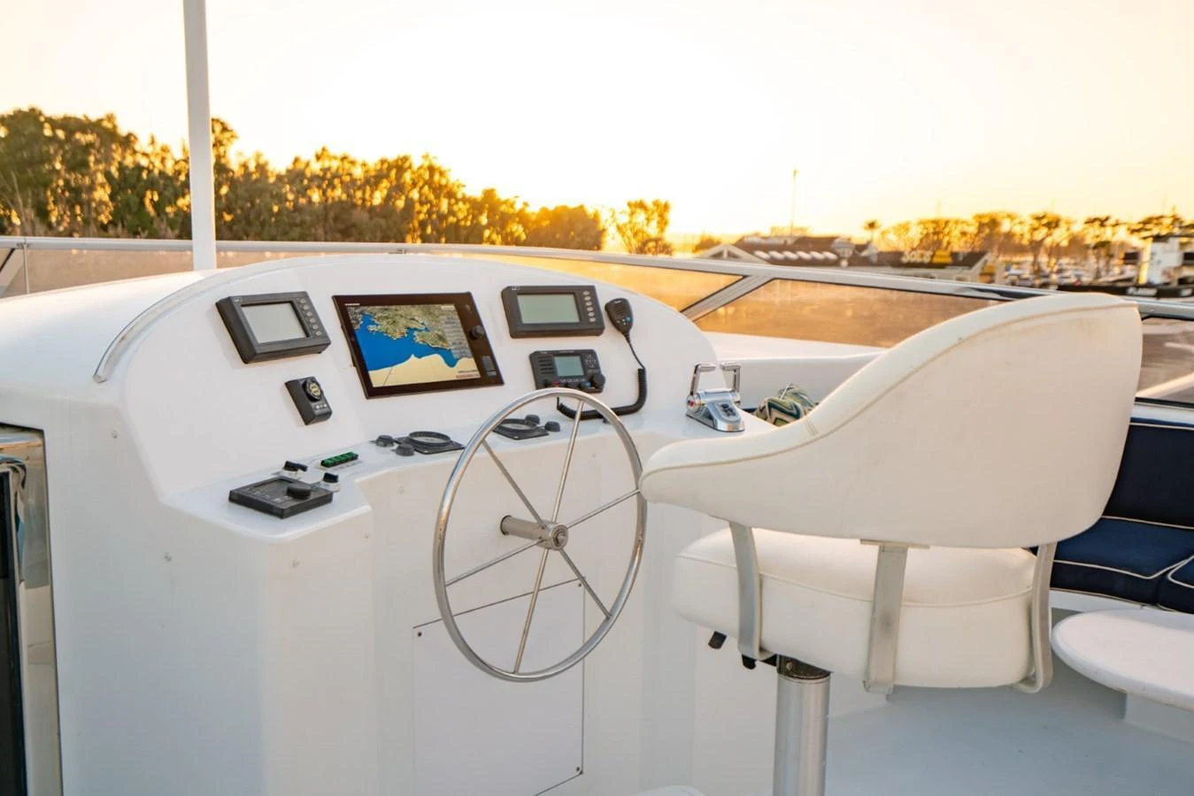 The helm station features modern navigation equipment and a comfortable captain's chair, bathed in warm sunset light. aboard SNOWBORED Yacht for Sale