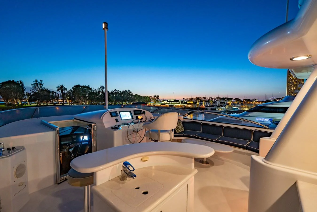 The flybridge offers a luxurious space with modern navigation equipment and a stunning view of the marina at dusk. aboard SNOWBORED Yacht for Sale
