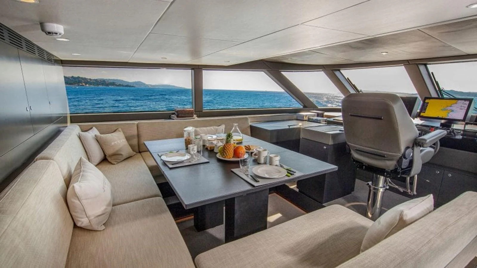 The salon offers a comfortable seating area with panoramic ocean views and a dining setup. aboard JANGADA Yacht for Sale