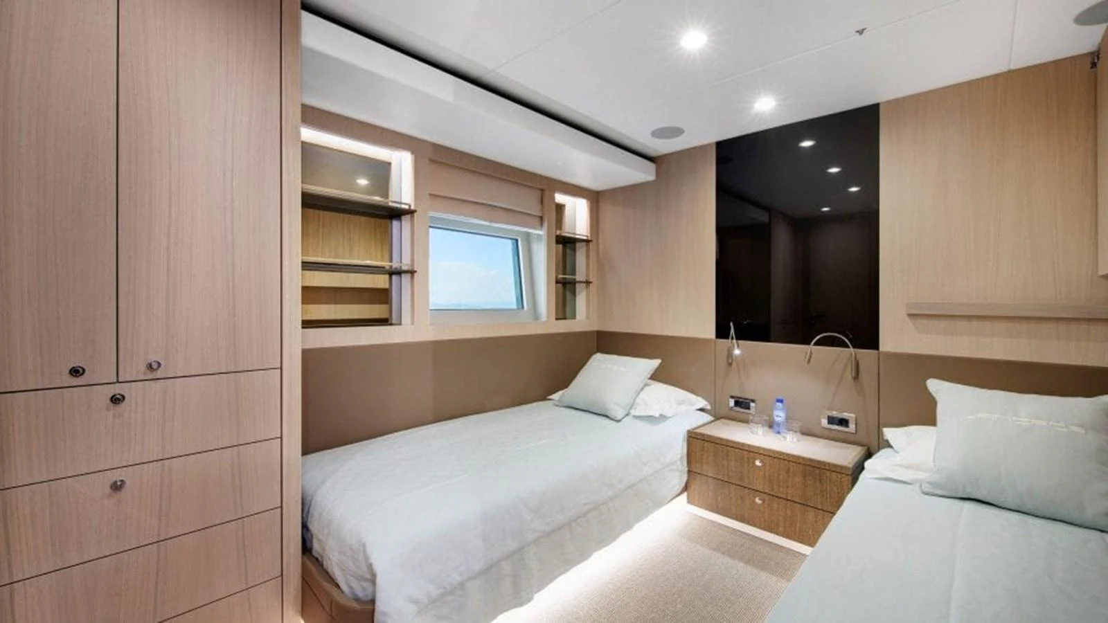 The guest stateroom features twin beds and a serene, modern design with ample storage and natural light. aboard JANGADA Yacht for Sale