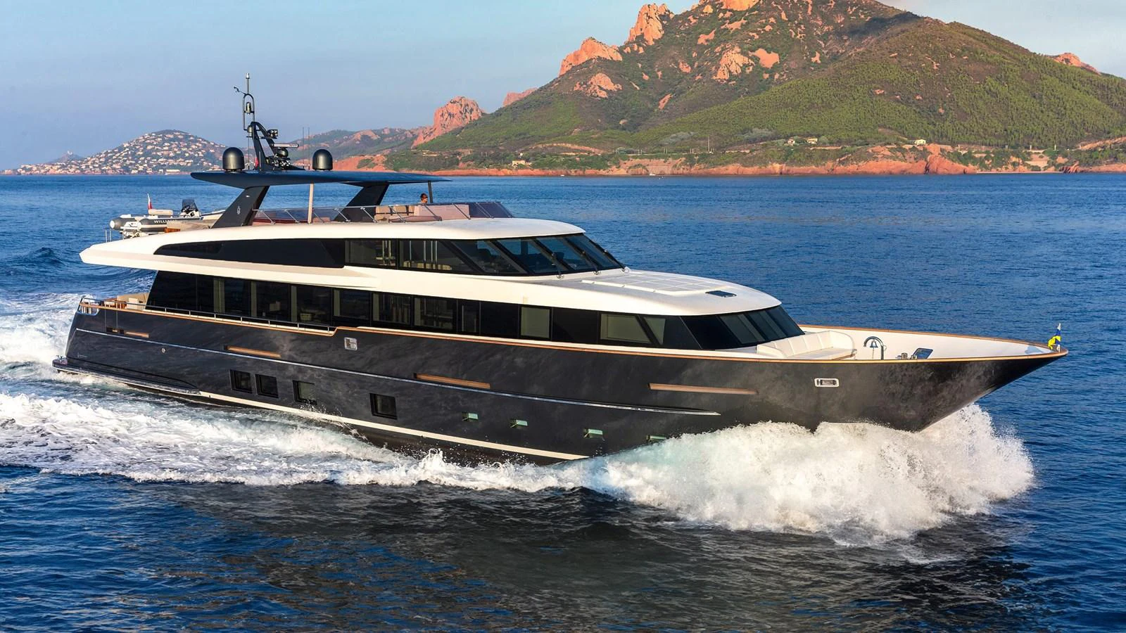 A sleek and modern yacht cruises through the water with a stunning coastal backdrop. aboard JANGADA Yacht for Sale