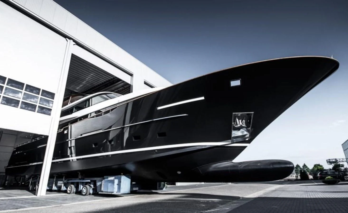 The sleek black yacht is being moved out of a large industrial building, showcasing its modern design and impressive size. aboard JANGADA Yacht for Sale