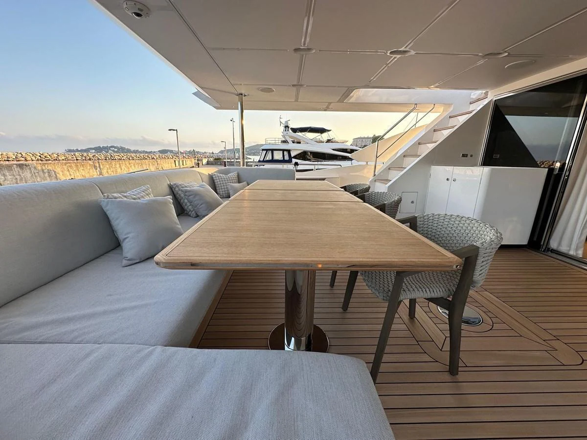 The aft deck features a comfortable seating area with a wooden table, perfect for outdoor dining and relaxation. aboard G Yacht for Sale