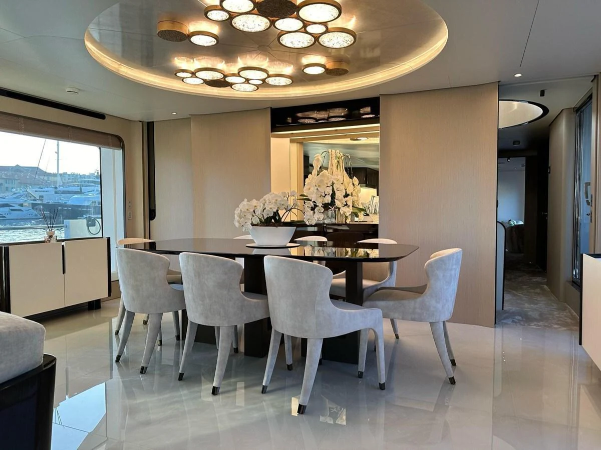 The yacht's dining area features a modern table with elegant seating and a stunning ceiling light fixture. aboard G Yacht for Sale