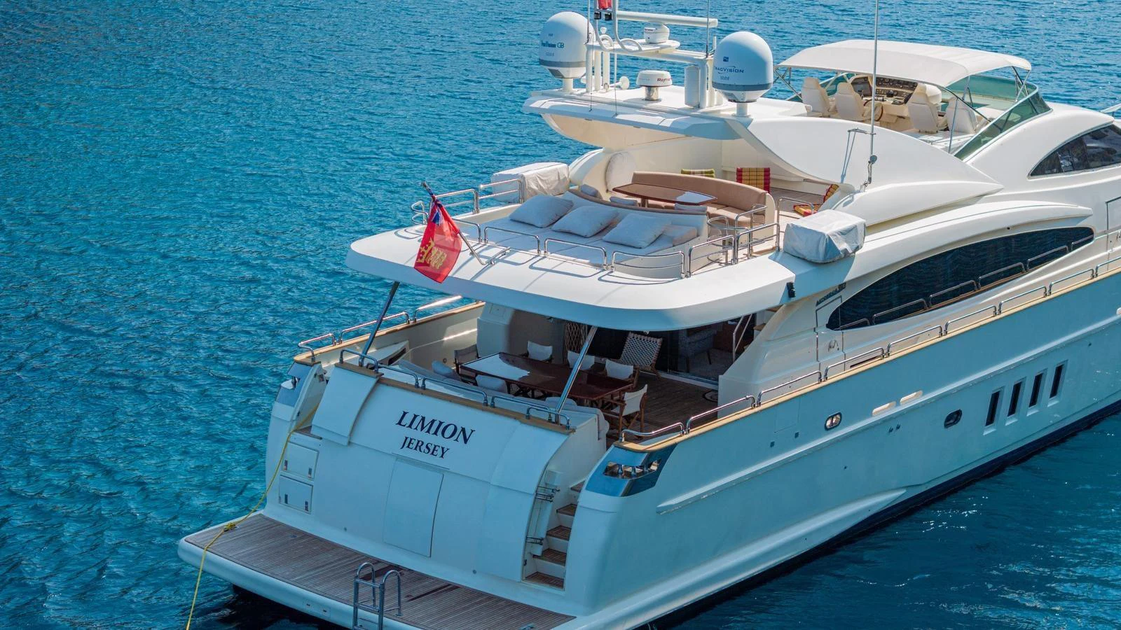 A luxurious yacht with an expansive aft deck and sleek design floats on clear blue waters. aboard LIMION Yacht for Sale