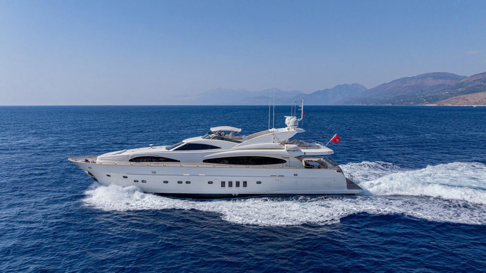 A sleek and elegant yacht cruises through the open sea under a clear blue sky. aboard LIMION Yacht for Sale