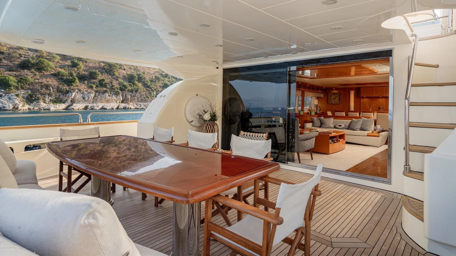 The aft deck features a spacious dining area with a view into the luxurious interior salon. aboard LIMION Yacht for Sale