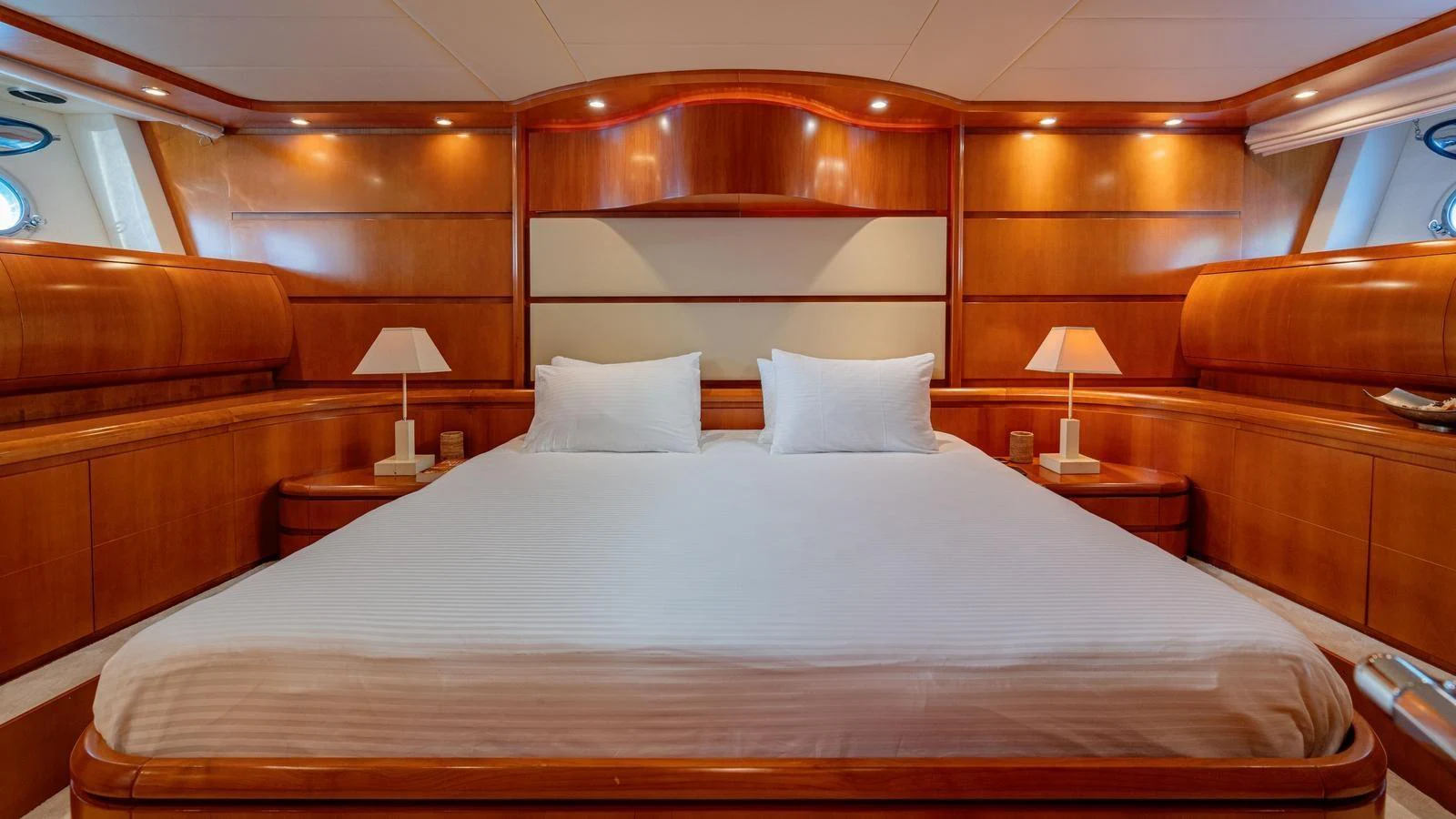 The master stateroom features a spacious bed with elegant wooden furnishings and ambient lighting. aboard LIMION Yacht for Sale