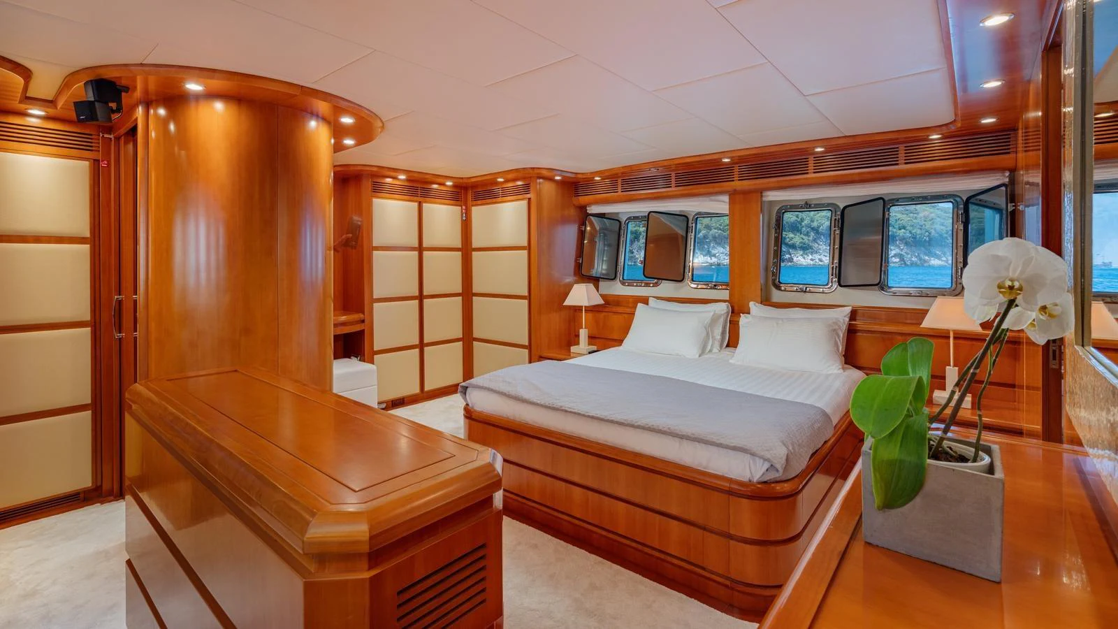 The master stateroom features elegant wood paneling, a large bed, and ample natural light from the windows. aboard LIMION Yacht for Sale