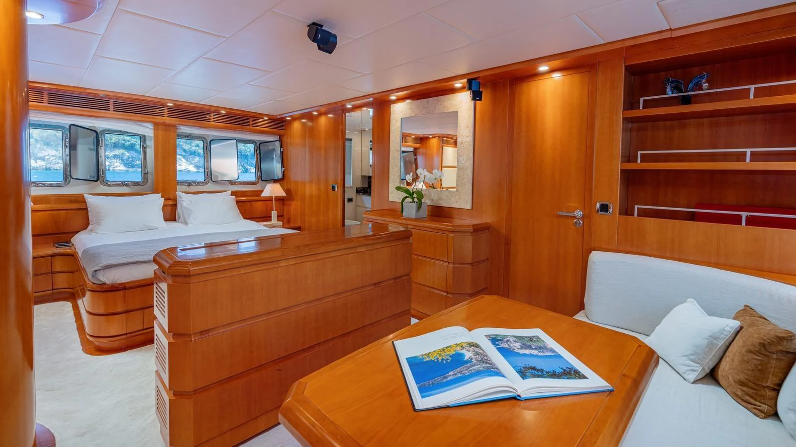 The stateroom features a cozy seating area, a comfortable bed, and ample wooden cabinetry. aboard LIMION Yacht for Sale