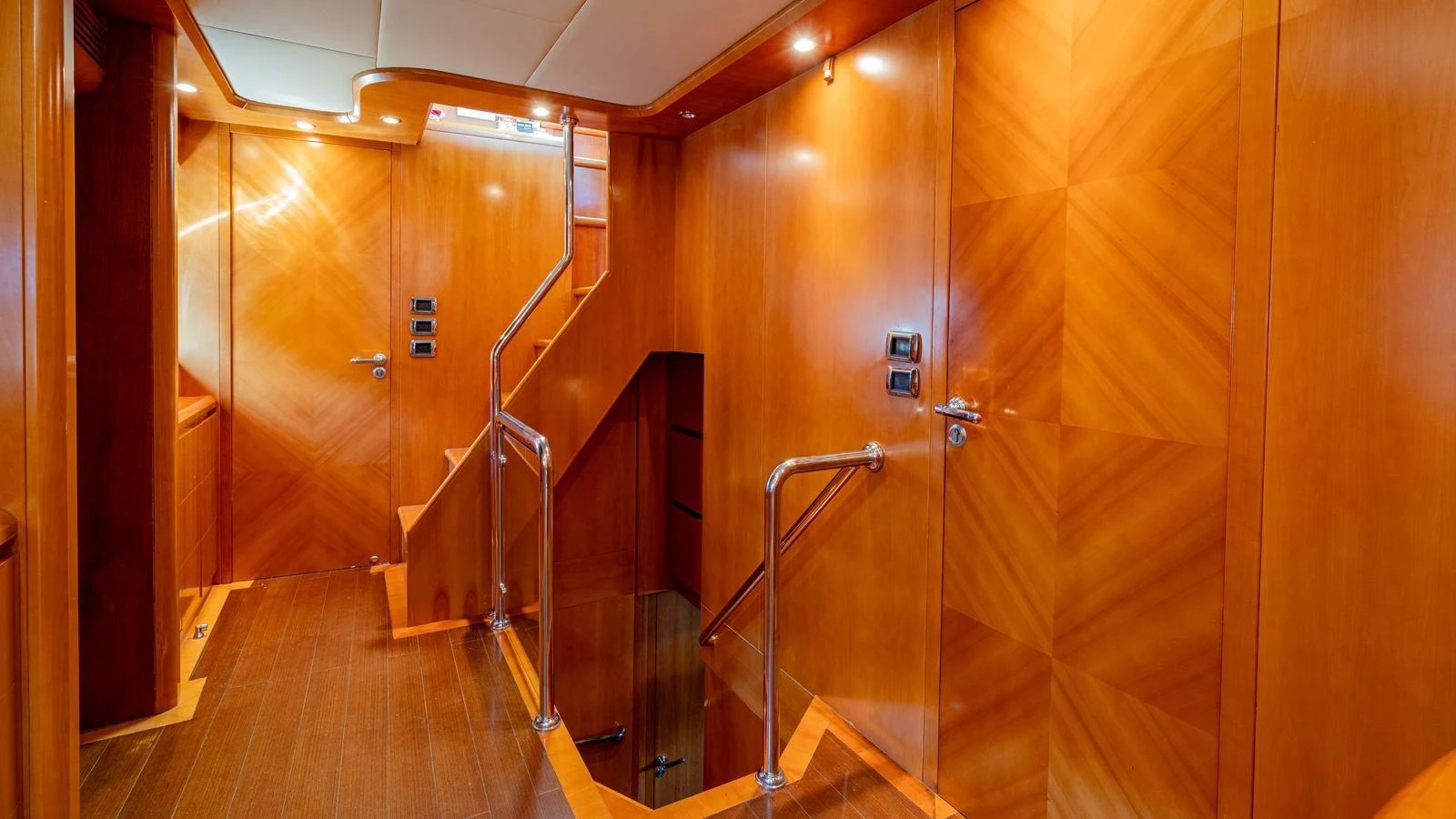 The yacht's interior features a polished wooden hallway with modern lighting and sleek railings. aboard LIMION Yacht for Sale