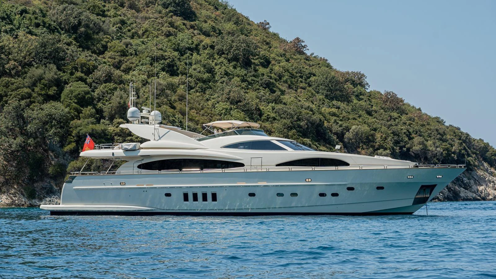 A sleek and modern yacht cruising along a lush, green coastline. aboard LIMION Yacht for Sale