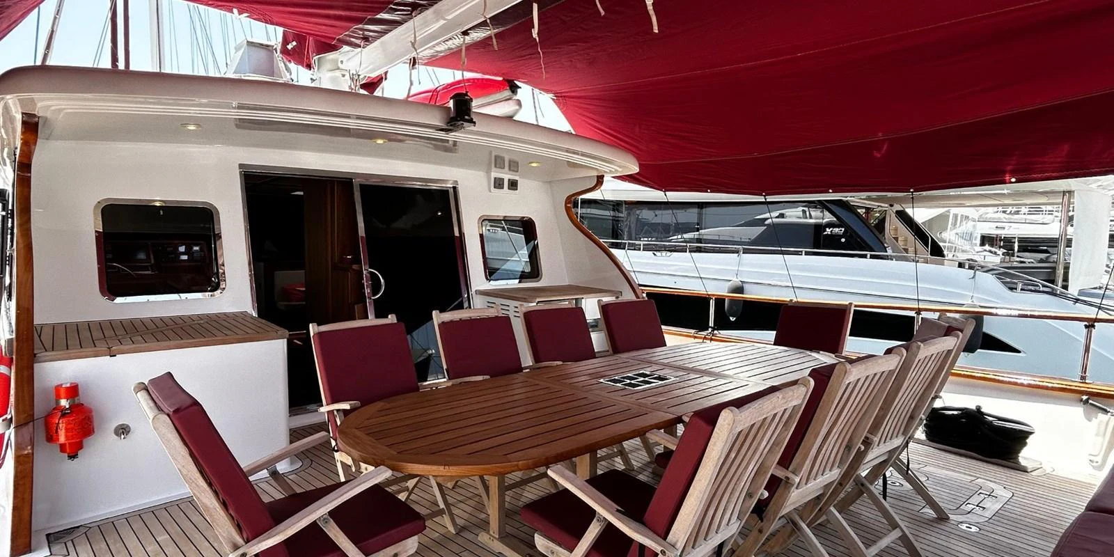 The aft deck features a spacious dining area with a large wooden table and comfortable seating, perfect for alfresco meals. aboard AKHENATON Yacht for Sale