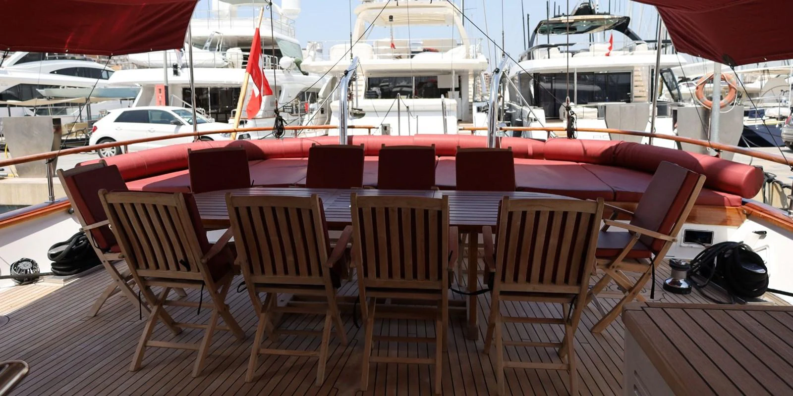 The aft deck features a spacious dining area with wooden chairs and a large table, perfect for alfresco dining. aboard AKHENATON Yacht for Sale