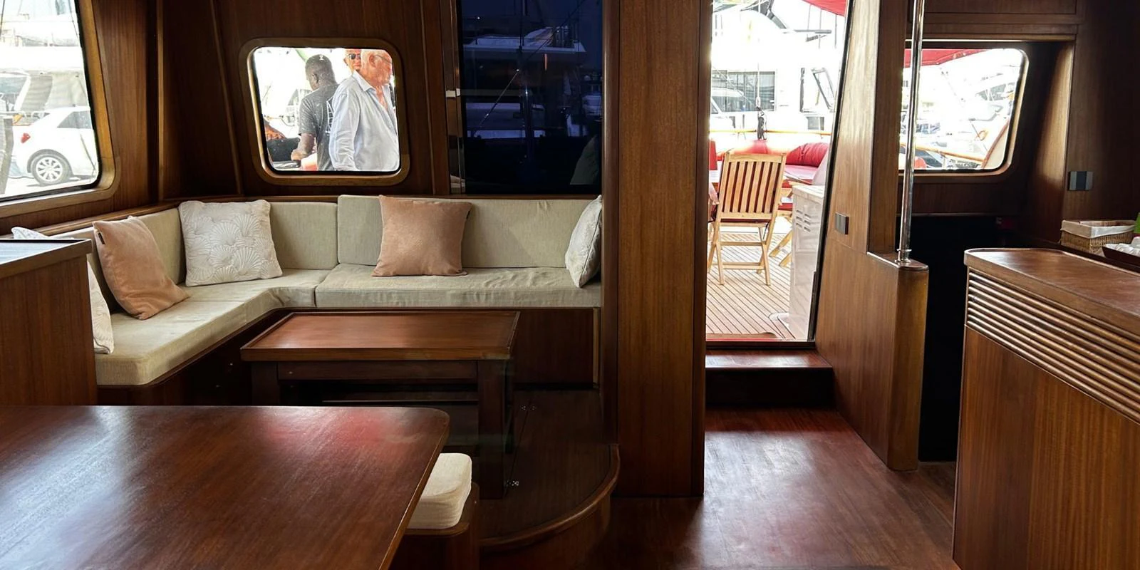 The yacht's salon features a cozy seating area with plush cushions and a wooden table, leading out to the deck. aboard AKHENATON Yacht for Sale