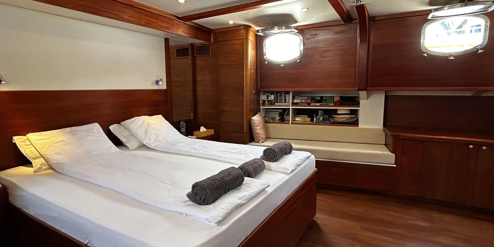 The stateroom features a cozy double bed with elegant wooden finishes and ample natural light. aboard AKHENATON Yacht for Sale