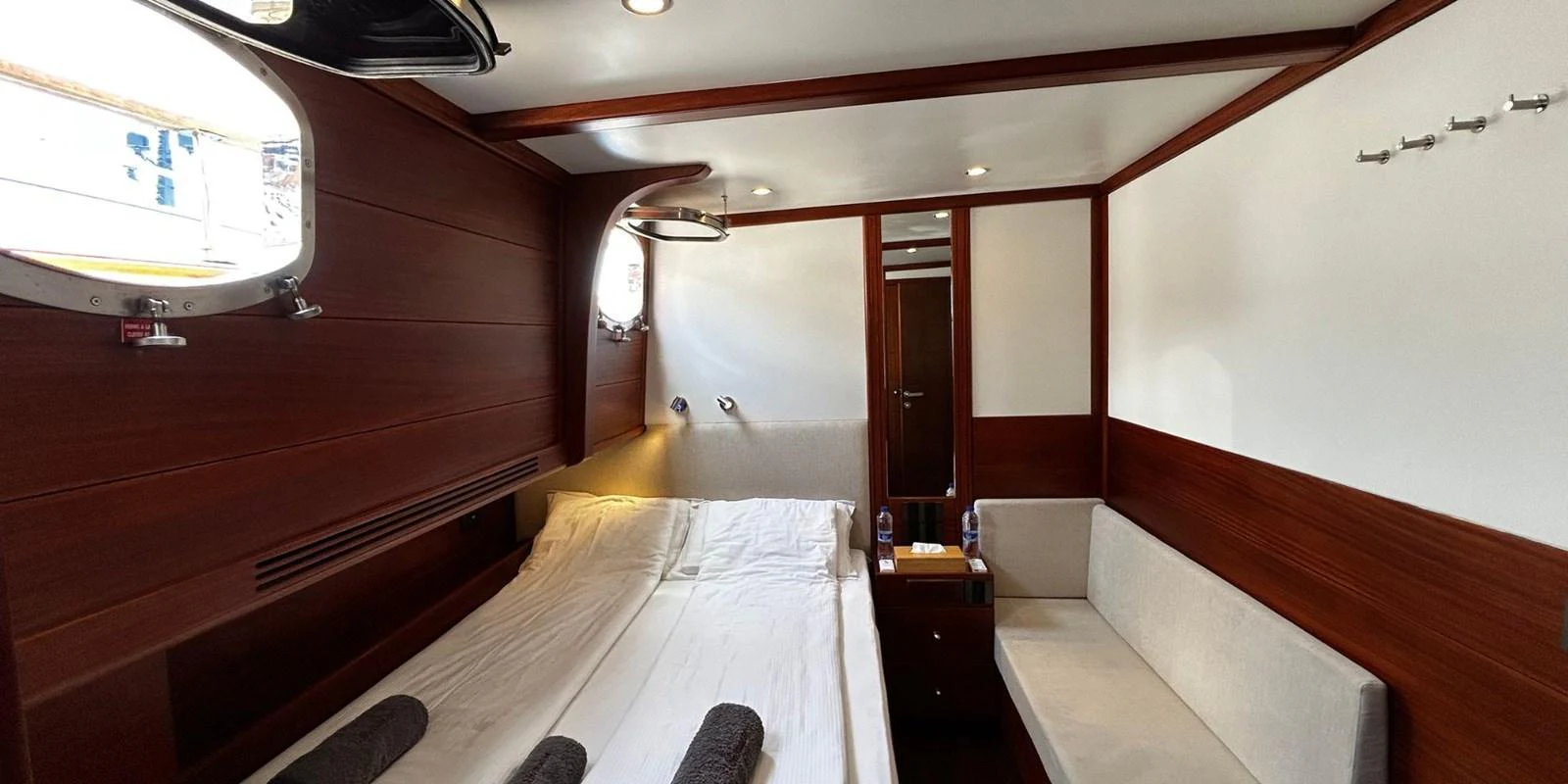 The cozy stateroom features a comfortable bed, a small sofa, and elegant wooden paneling. aboard AKHENATON Yacht for Sale