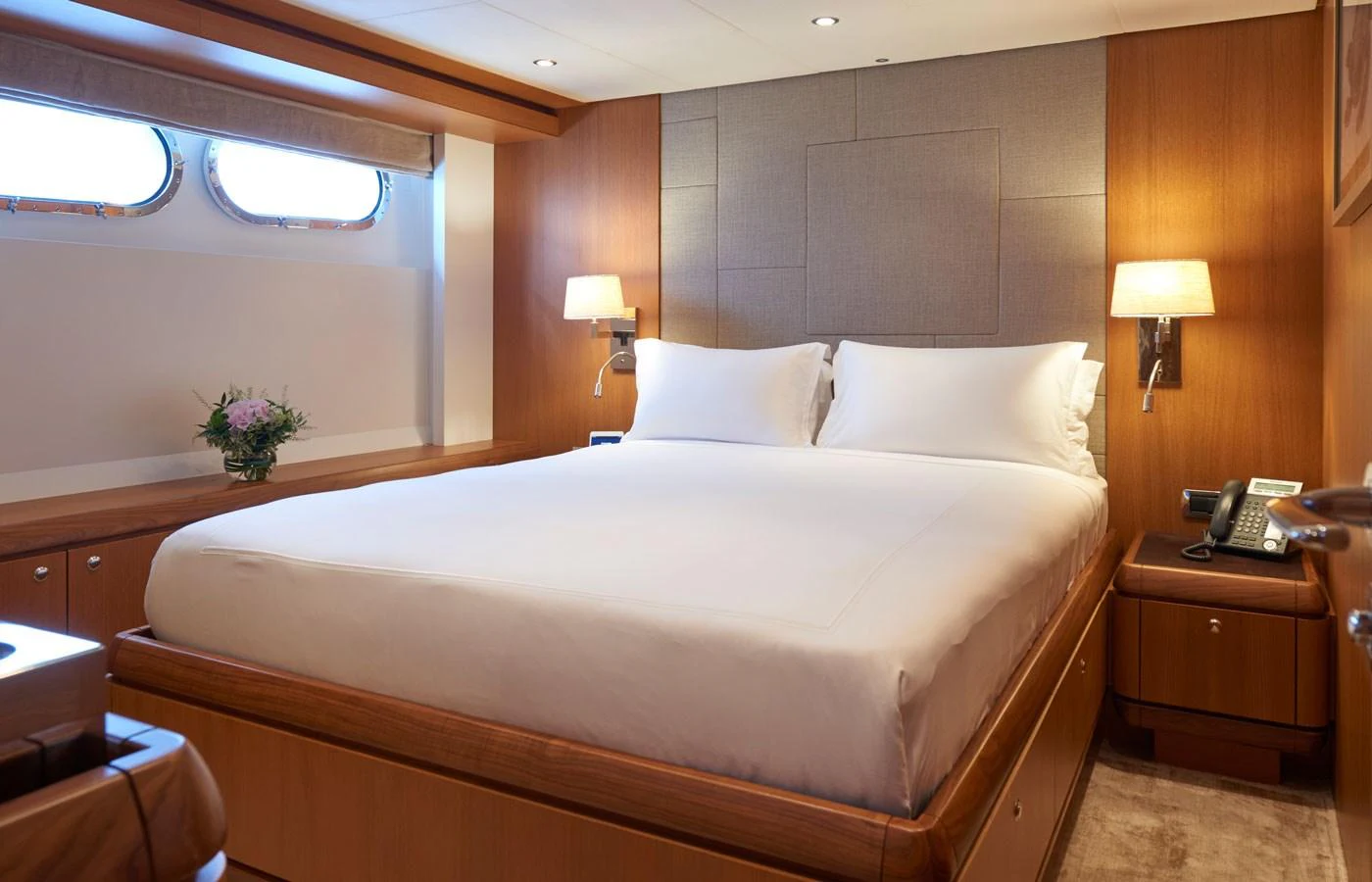 A cozy and elegantly designed stateroom featuring a large bed with crisp white linens and warm wood accents. aboard GALENA Yacht for Sale
