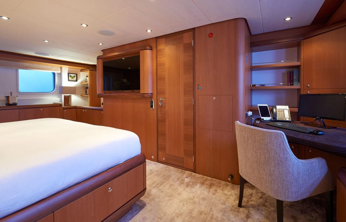 The master stateroom features elegant wood finishes and a spacious layout with a comfortable bed and a functional desk area. aboard GALENA Yacht for Sale