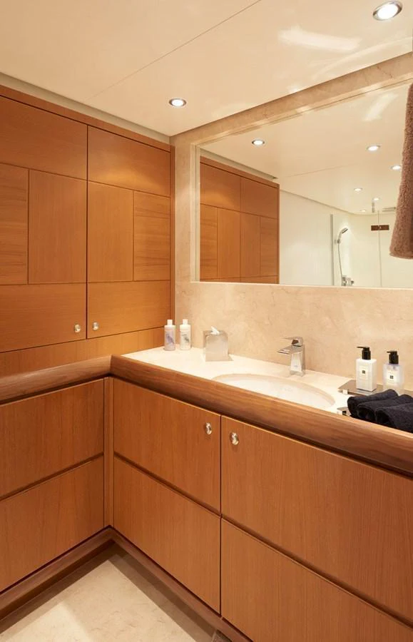The yacht's bathroom features elegant wood cabinetry and a spacious countertop with modern fixtures. aboard GALENA Yacht for Sale
