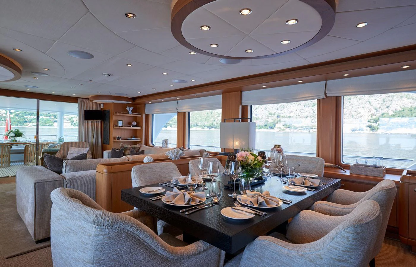 The yacht's dining area features an elegant table setting with plush seating and panoramic views through large windows. aboard GALENA Yacht for Sale
